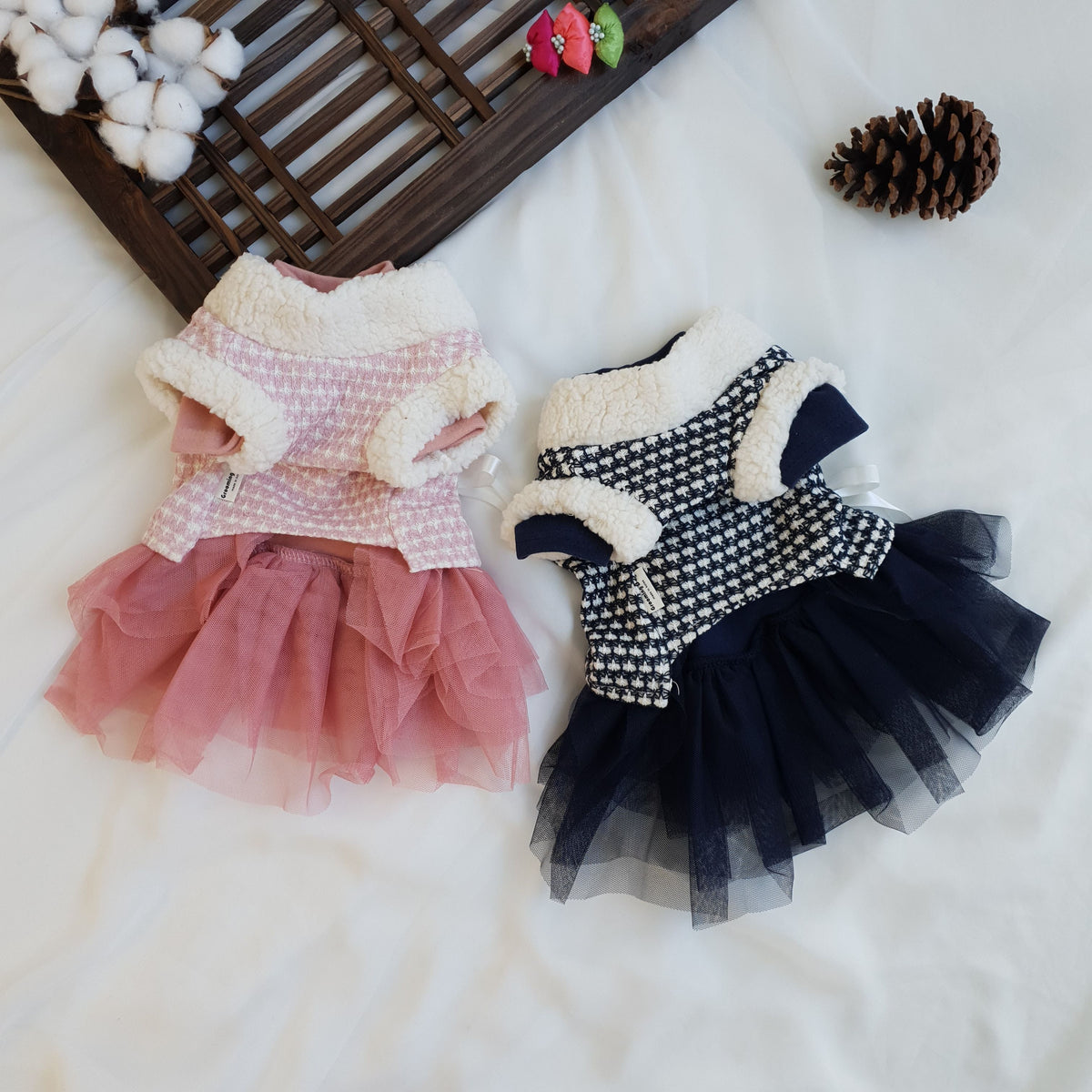 Two pet hanbok dresses featuring houndstooth pattern vests with tulle skirts in pink and navy blue.