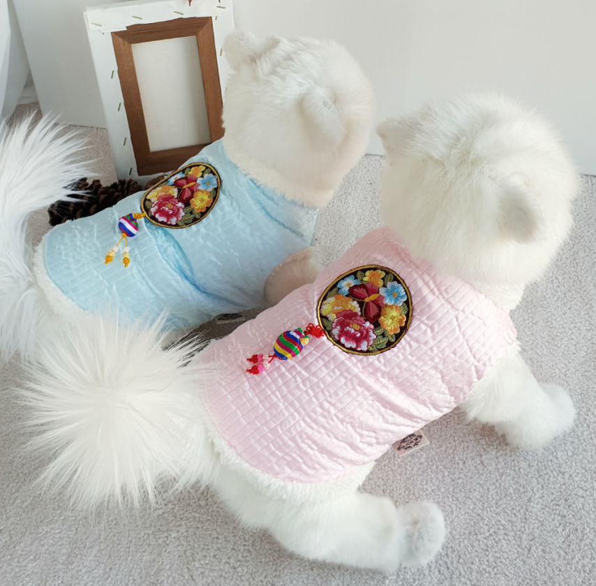 Pastel quilted pet hanbok vests in light blue and pink with floral embroidery and norigae tassels.