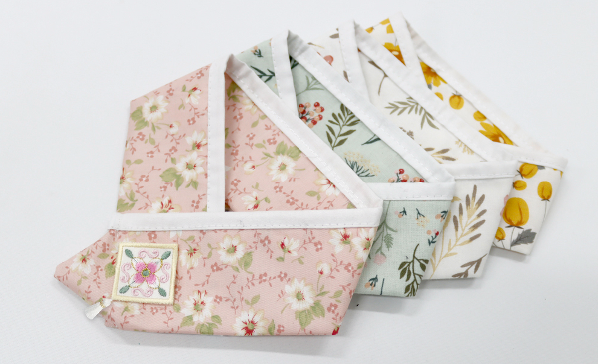 Set of floral patterned pet hanbok capes in pink, green, and yellow.