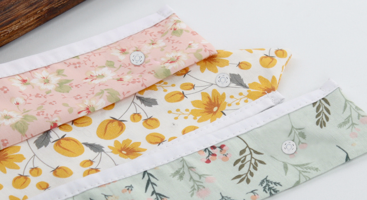 Three floral pattern pet hanbok capes in pink, yellow, and light green.