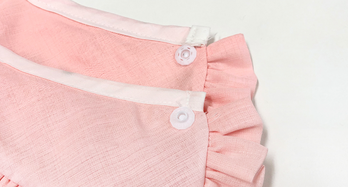 Close-up of a pink NKpup Ruffle Pet Hanbok Cape featuring white trim and button closures.