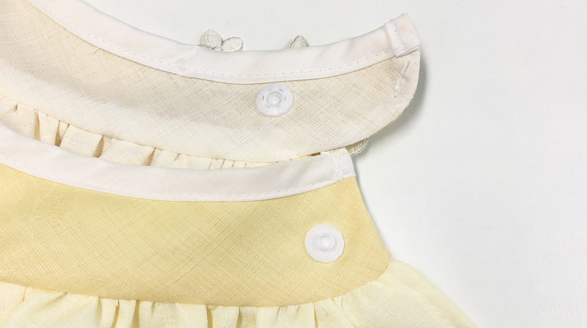Close-up of a white and pale yellow floral ruffle pet hanbok cape with button details.