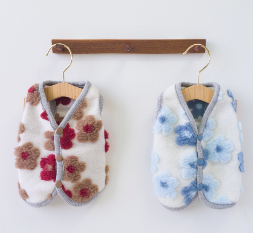 Two NKpup floral fleece dog vests, one with red and brown flowers and one with blue flowers.