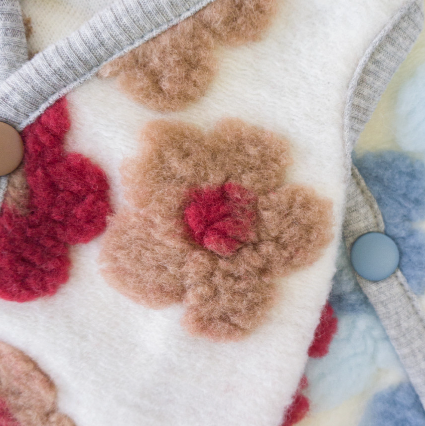 White floral fleece dog vest with brown and red flower patterns and grey trim.