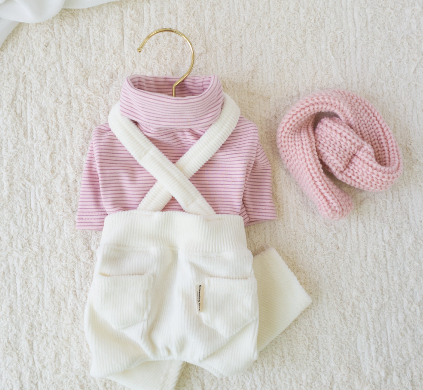 Pink turtleneck dog shirt with white corduroy suspender overalls and matching knit scarf.