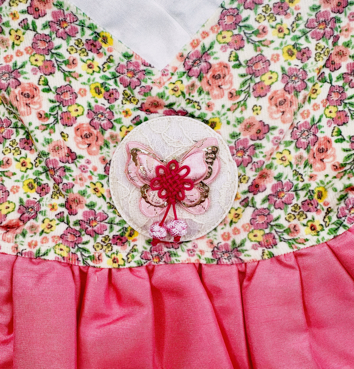 Detail of a retro floral NKpup pet hanbok with a pink butterfly norigae ornament.
