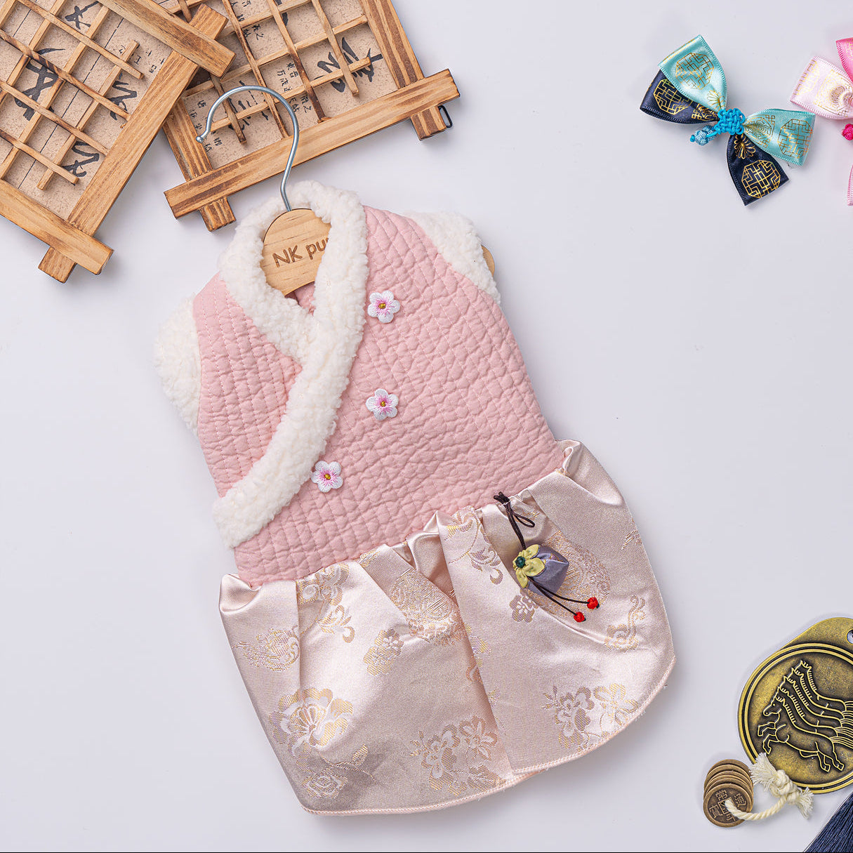Pink baby outfit with white fur trim on a light gray background