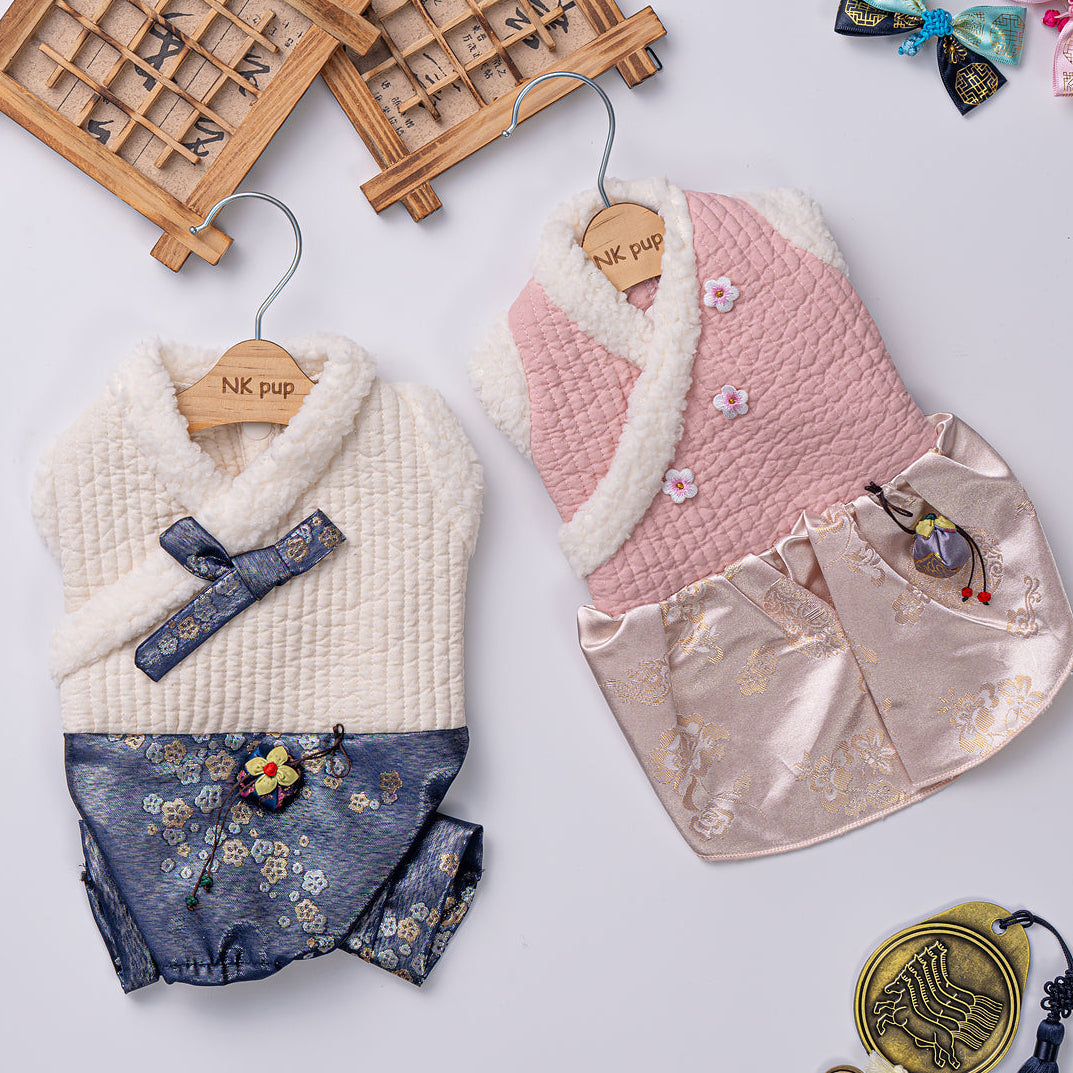 Two baby rompers with floral details on hangers against a light background.