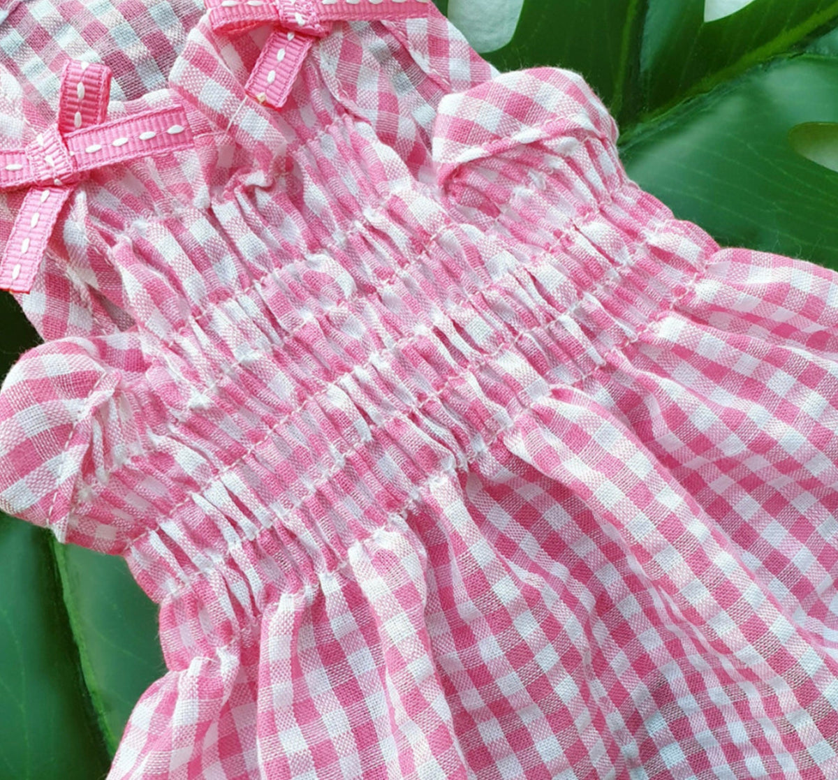 Pink and white vintage gingham dog dress with smocked waist and bow details.