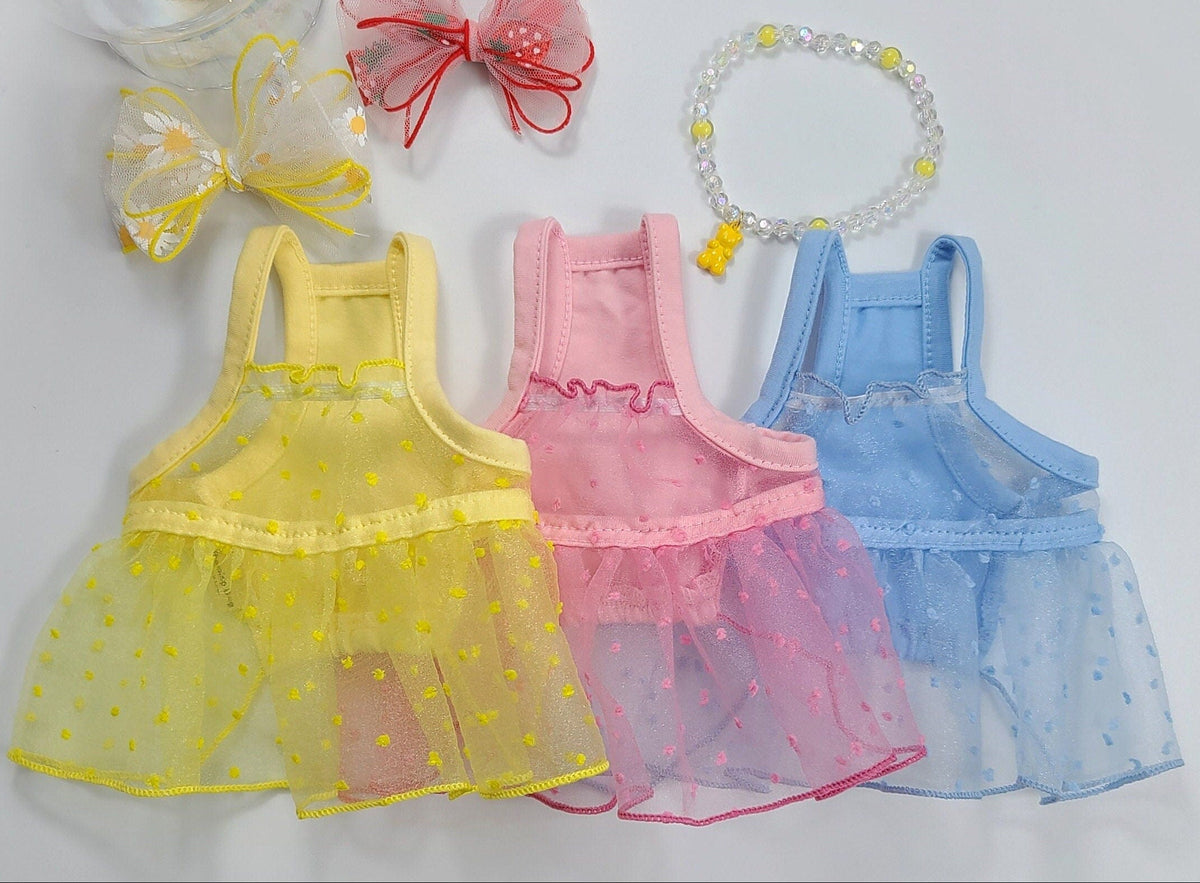 Set of three lace pet dresses in yellow, pink, and blue with matching bows and a beaded bracelet.