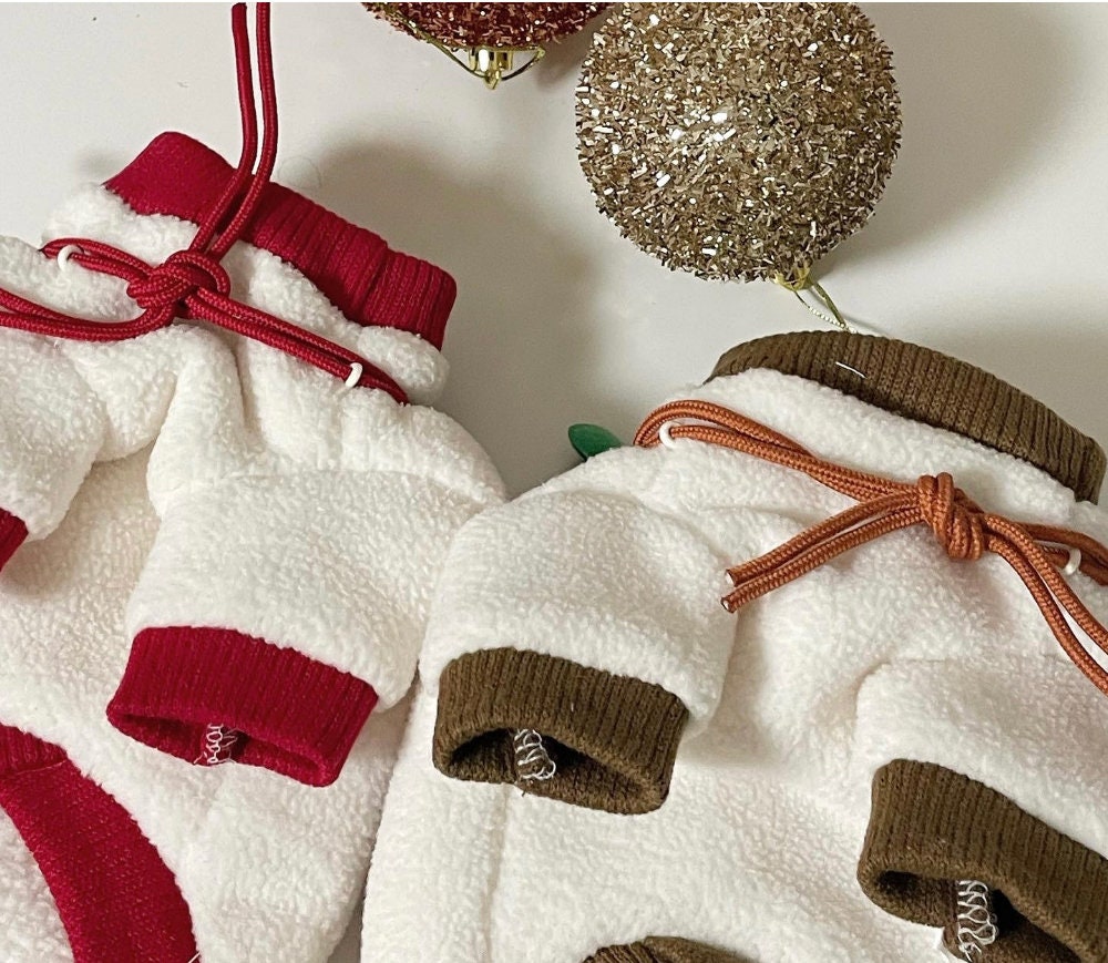 White Christmas dog sweatshirts with red and brown ribbed trim and drawstring details.