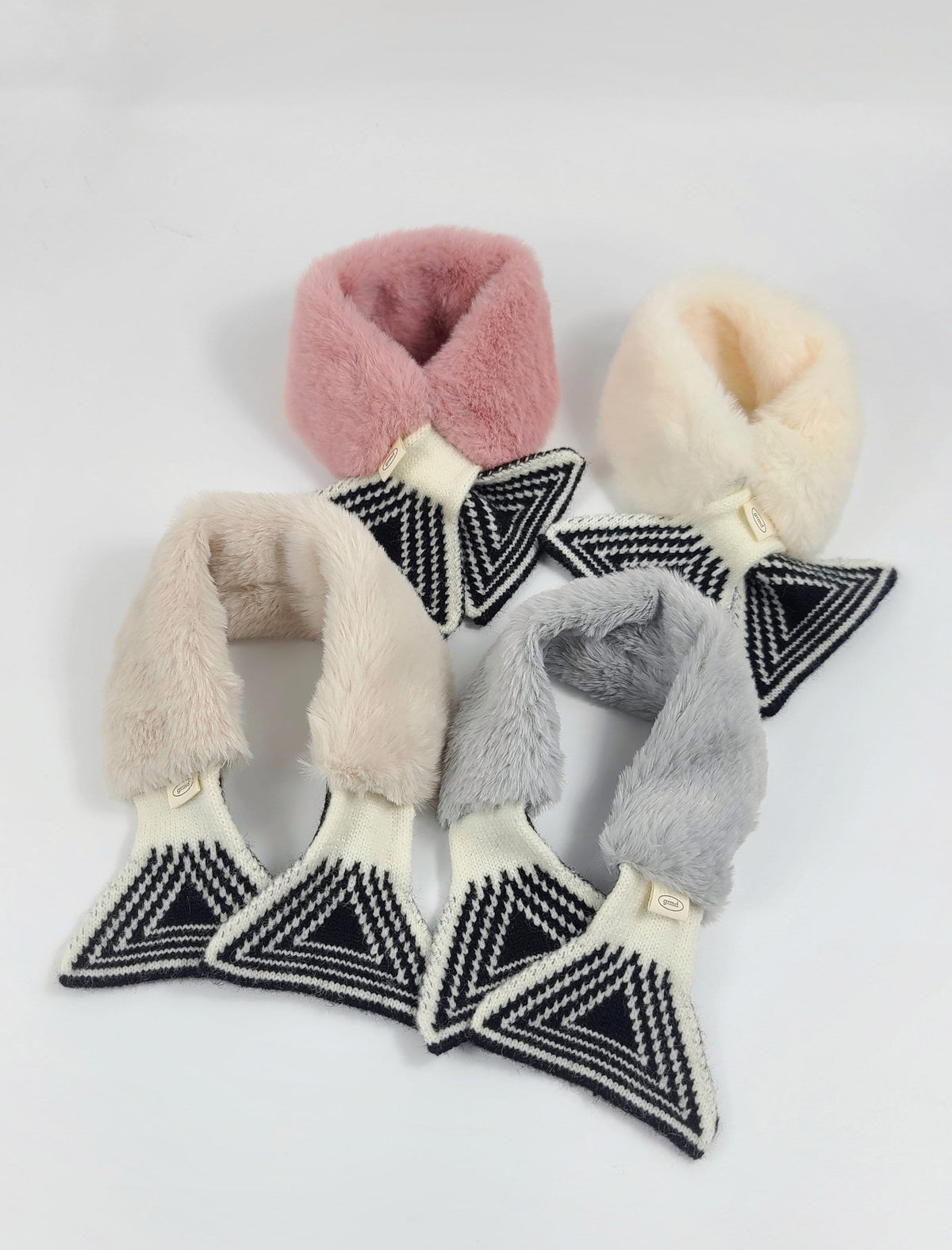 Set of four NKpup fur mufflers in pink, cream, beige, and grey with black and white geometric patterns.