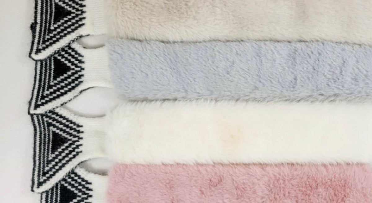 Set of four NKpup fur mufflers in beige, grey, white, and pink with black and white geometric patterned ends.
