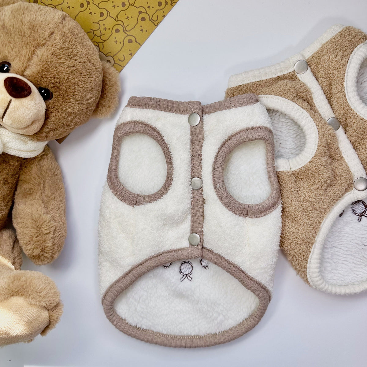 White and tan downy fleece dog vest with snap button closures.