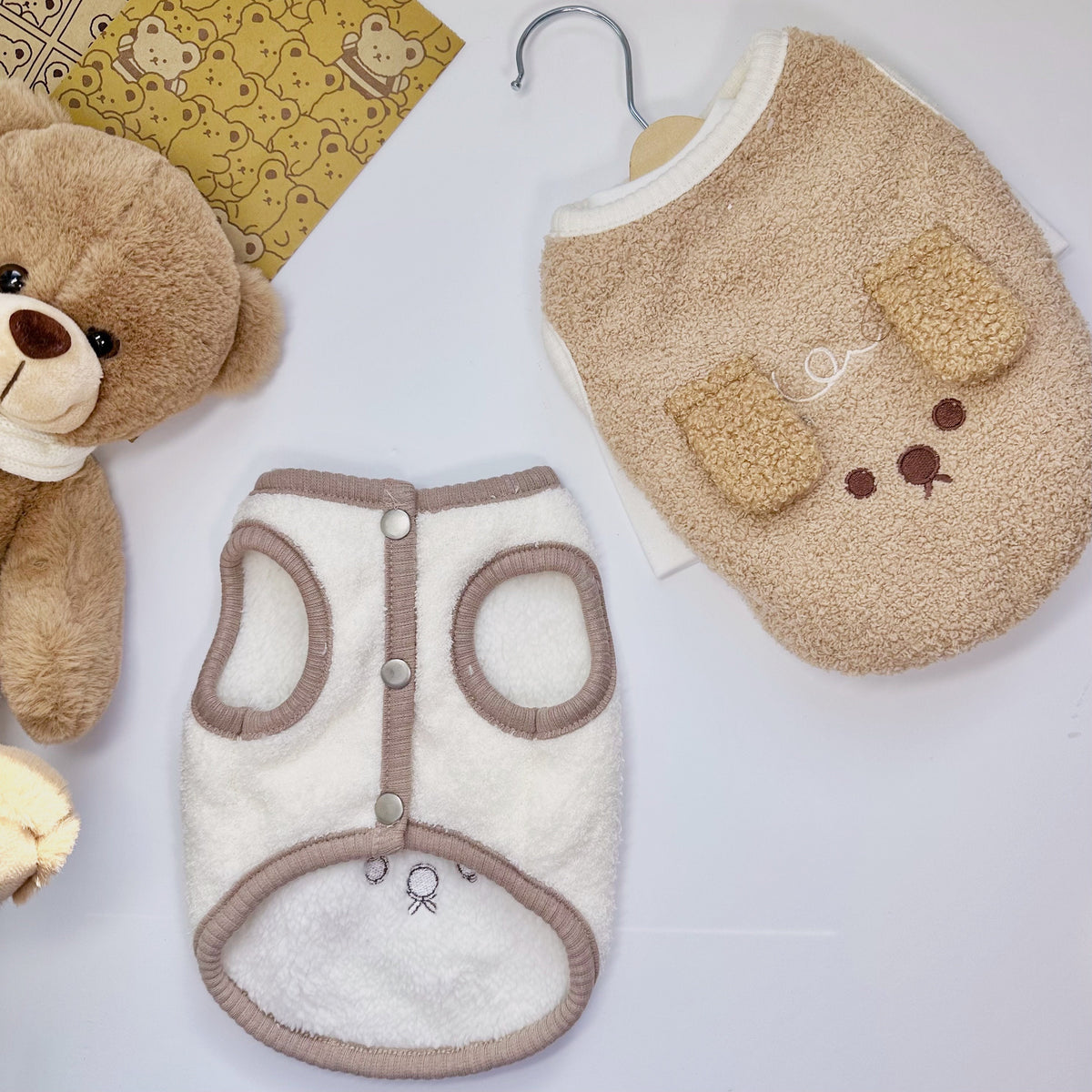 Downy fleece dog vest in beige and white with teddy bear face details.