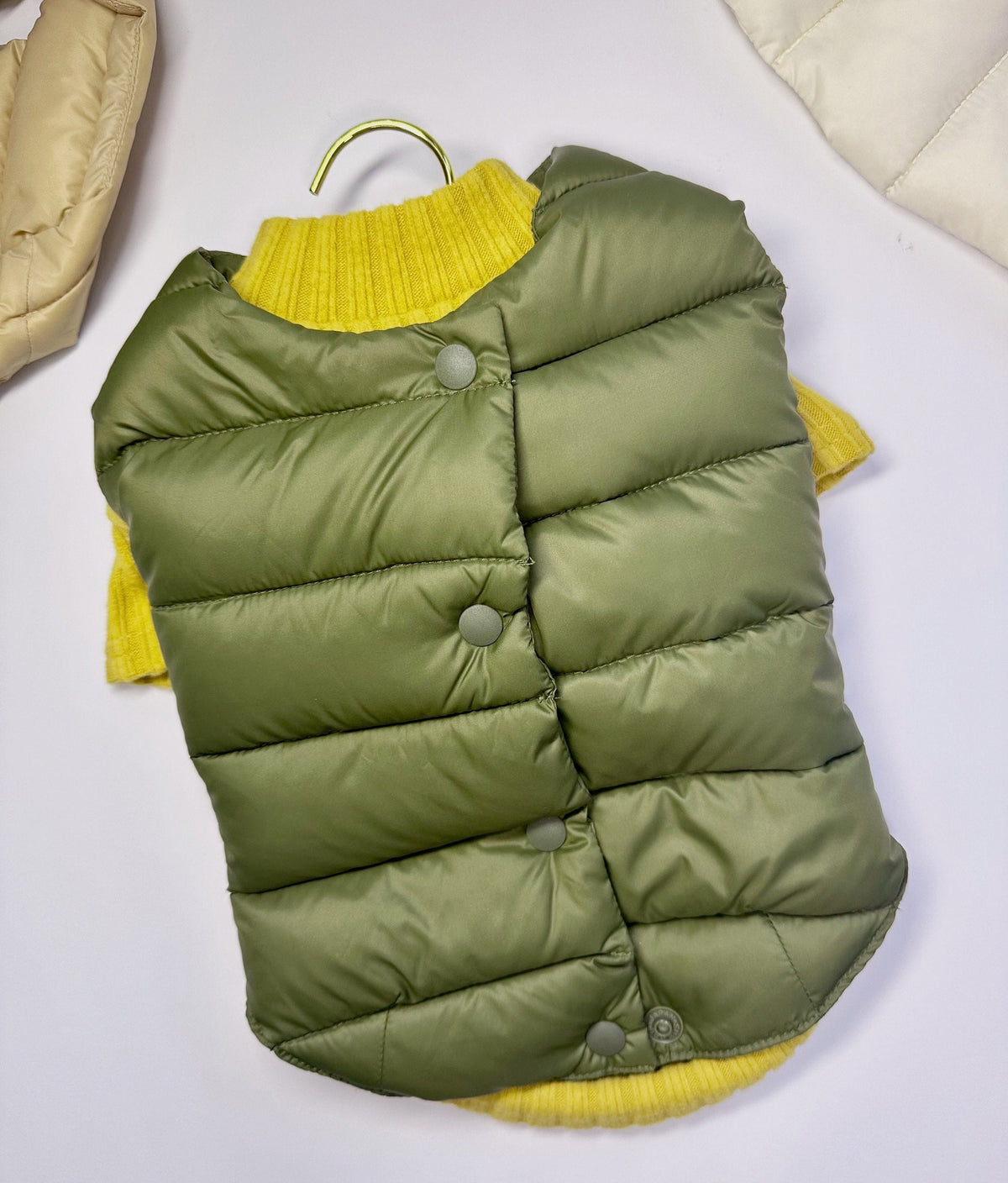 NKpup olive green duck down dog vest layered over a yellow knit sweater