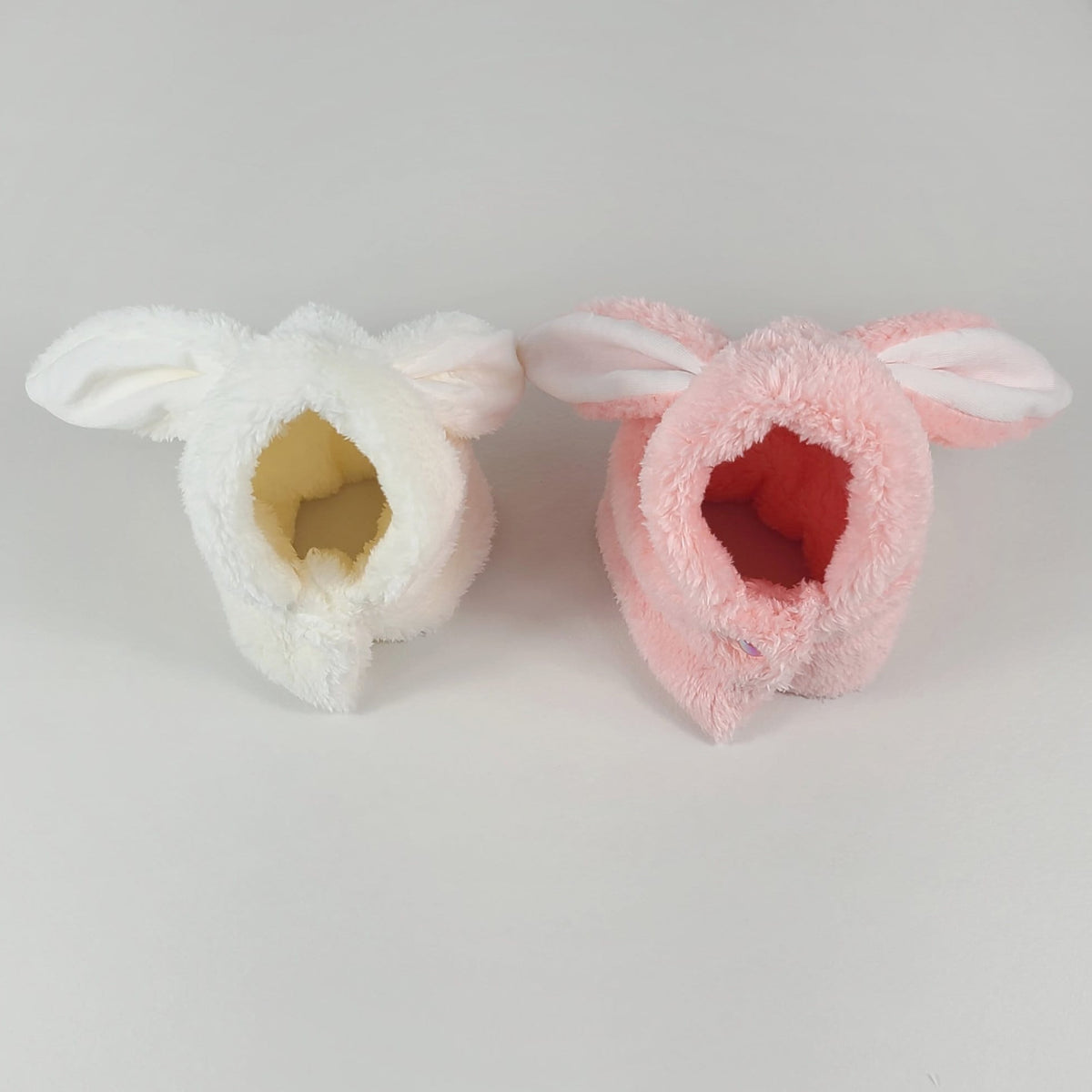 Two plush rabbit ear pet hoodies, one in white and one in pink.