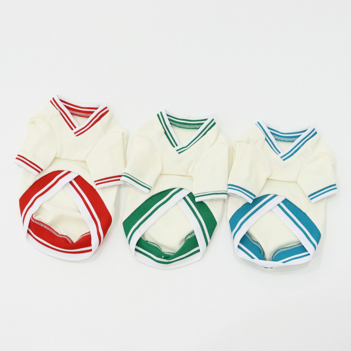 Three NKpup New York Jersey Tops for dogs in white with red, green, and blue striped accents.