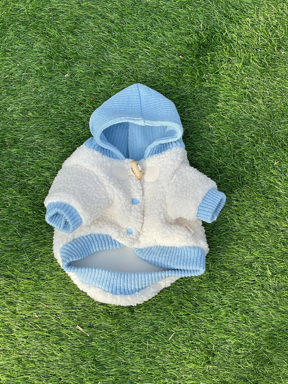White and light blue NKpup duffle fleece dog jacket with a hood and wooden button detail.