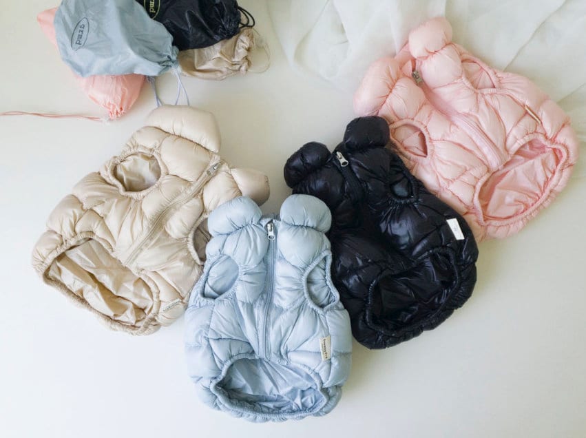 Collection of NKpup pastel puffer padded dog vests in light blue, beige, pink, and black.