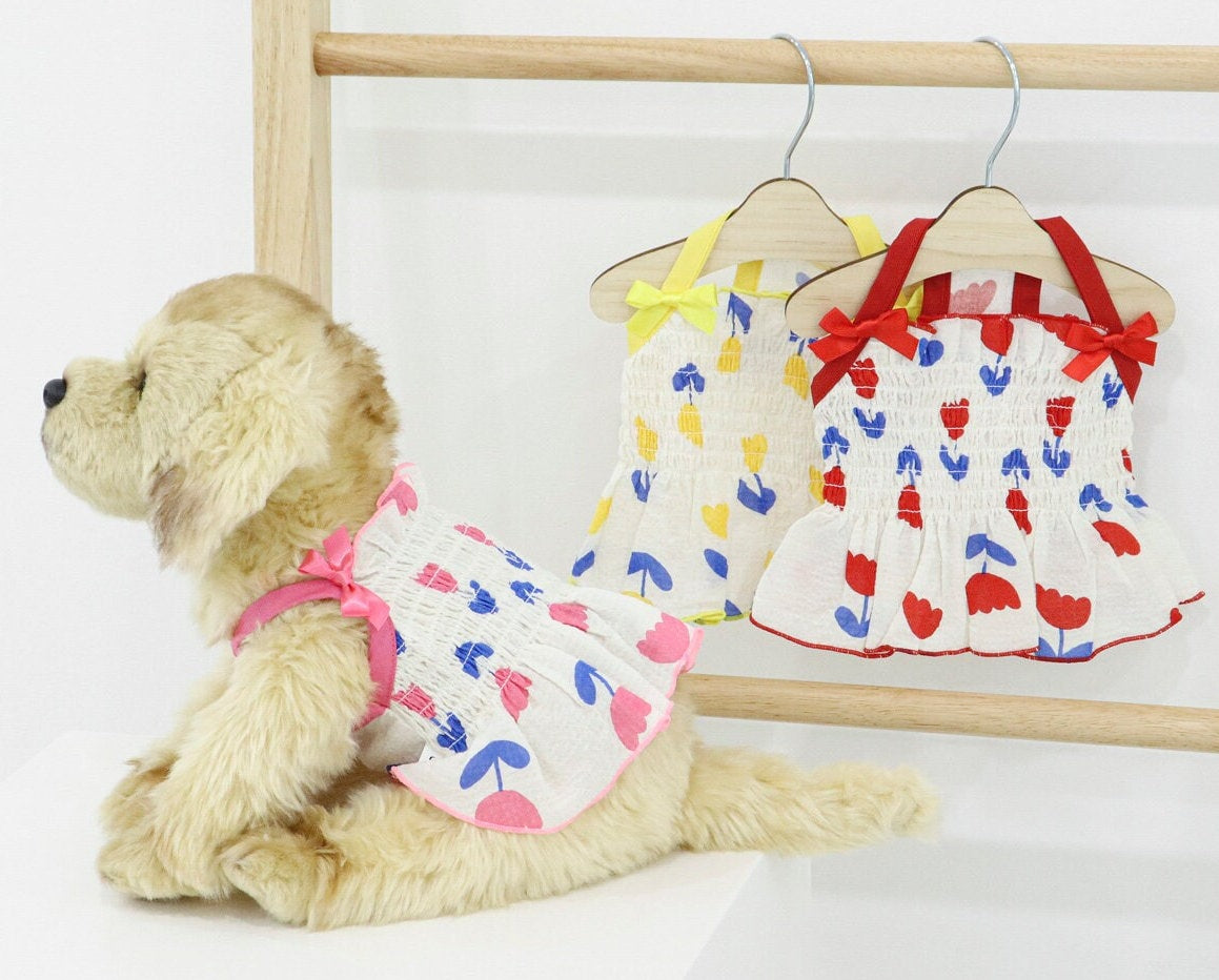 Tulip smocked dog dresses in white with yellow, red, and pink tulip patterns.