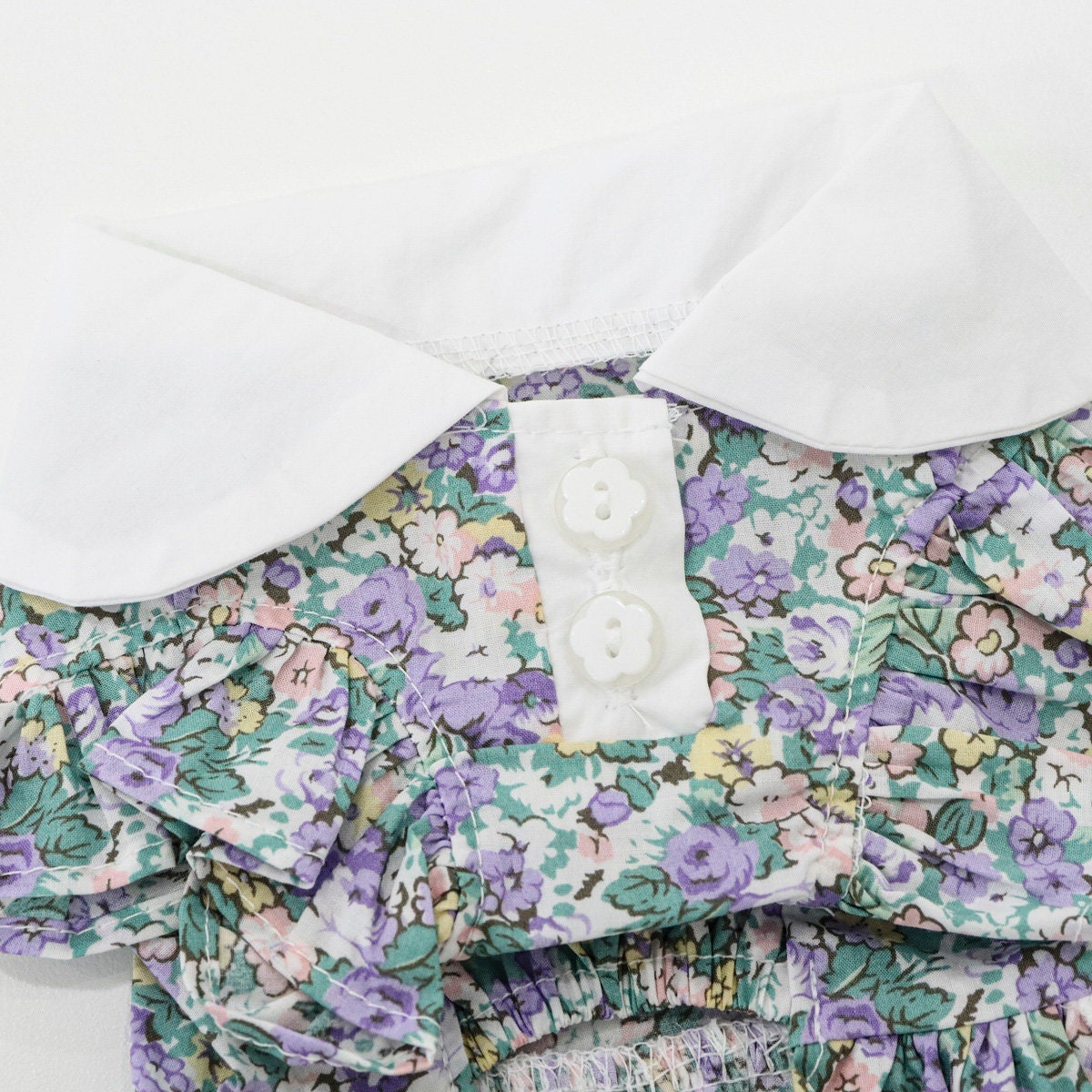 Floral Pinafore Dog Dress by NKpup featuring purple and green floral patterns with a white collar and buttons.