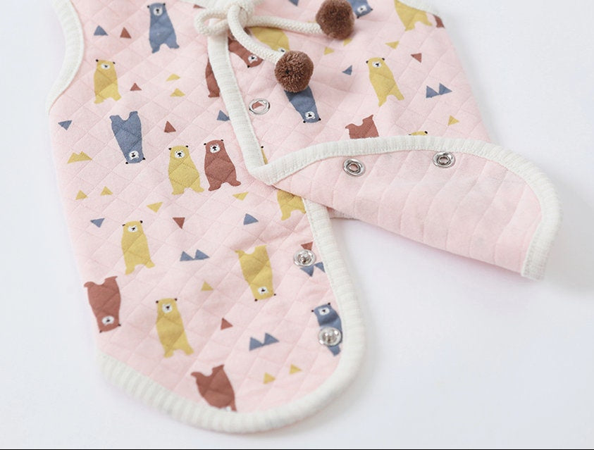 Pink quilted bear pattern dog vest with brown pom-poms and snap buttons