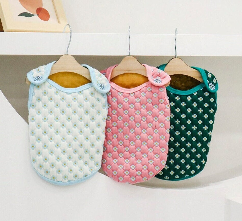 Three NKpup Daisy Quilted Dog Vests in light blue, pink, and dark green.