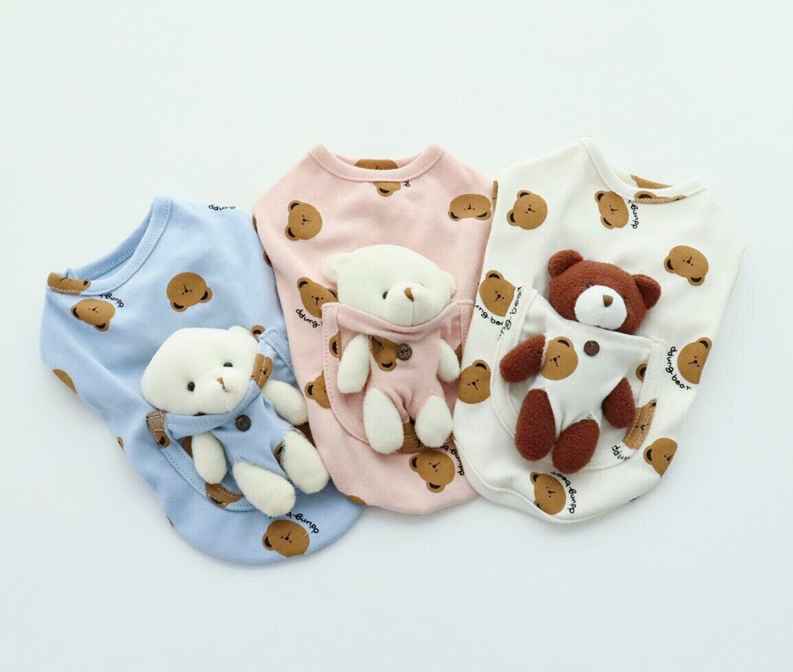 Three NKpup Bear Pocket Dog Shirts in blue, pink, and white with teddy bear patterns and plush bear pockets.