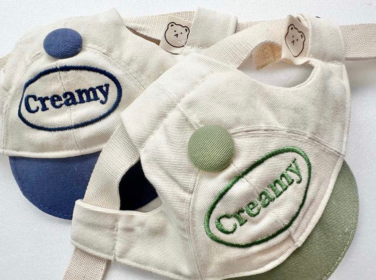Creamy Dog Cap Hat in cream and blue with embroidered logo and decorative button detail