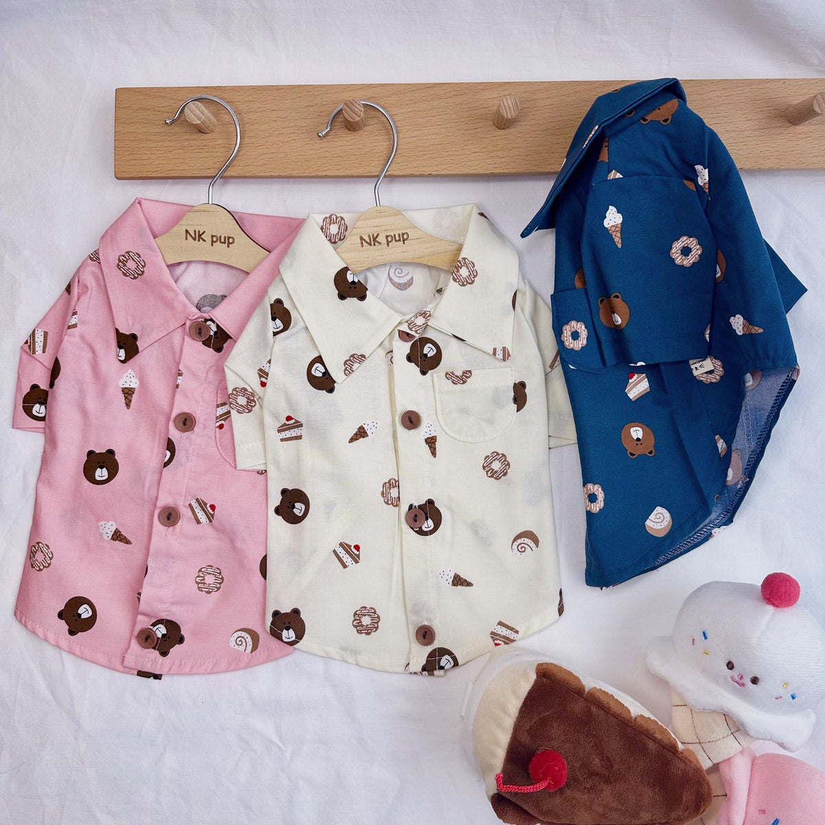 Three NKpup Sweet Treats Bear dog pajamas shirts in pink, cream, and blue with bear and dessert patterns.