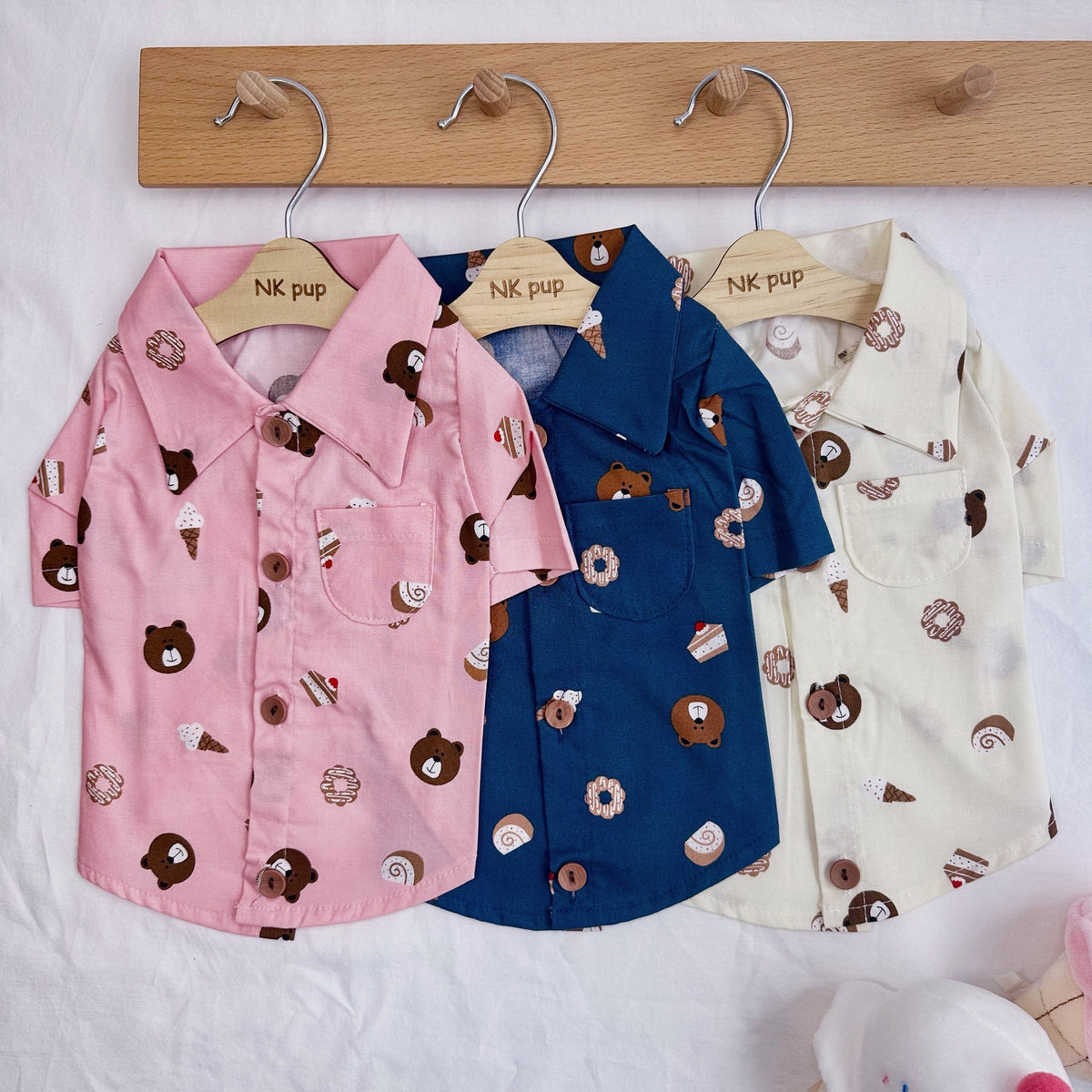 Three NKpup Sweet Treats Bear dog shirts in pink, blue, and cream with bear and dessert patterns.