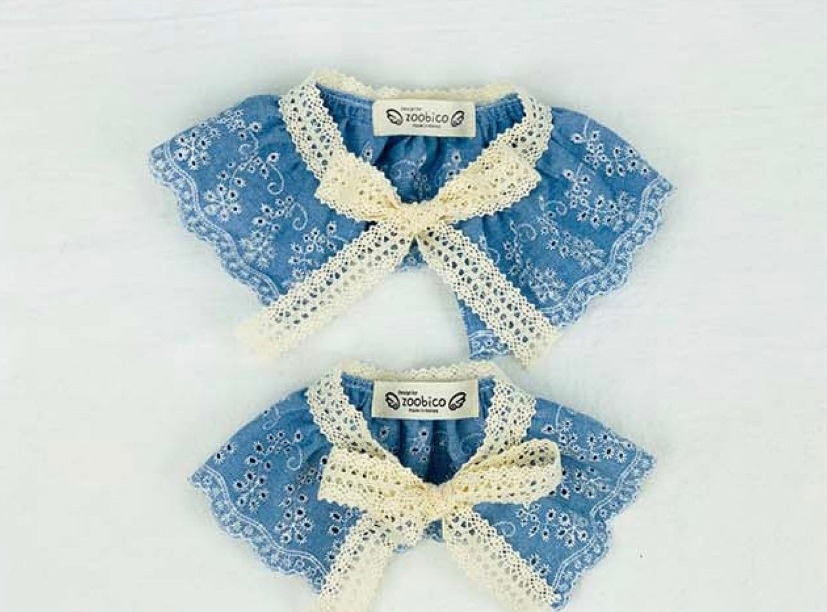 Two denim lace dog capes in blue with white floral patterns and cream lace trim.
