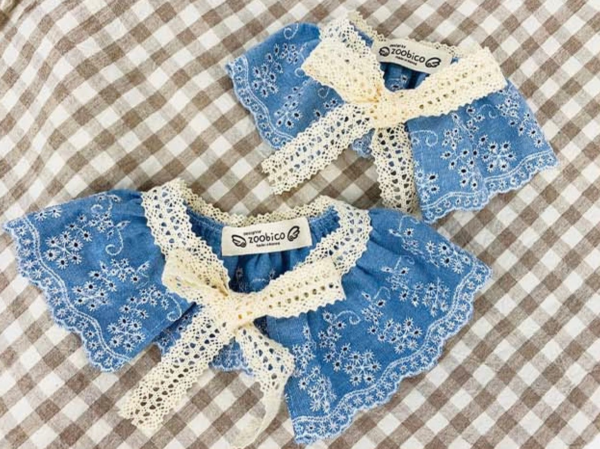 Blue denim lace dog cape with delicate white floral patterns and a lace tie.