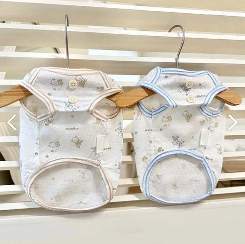 Two NKpup organic jacquard dog shirts with cute patterns in white, one with tan trim and one with blue trim.