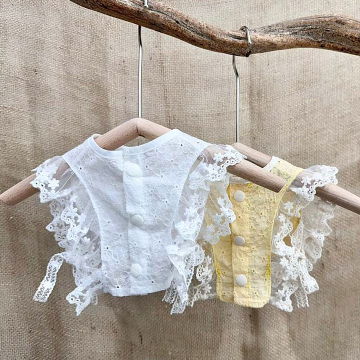 White and yellow cotton lace bibs for pets with ruffled edges and button details.