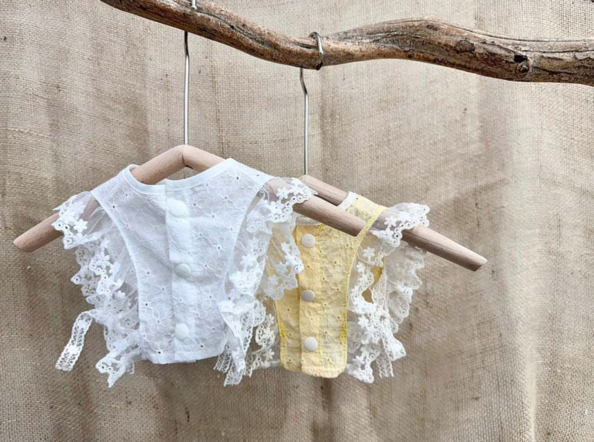 White and yellow cotton lace bibs for pets with ruffled edges and button details.