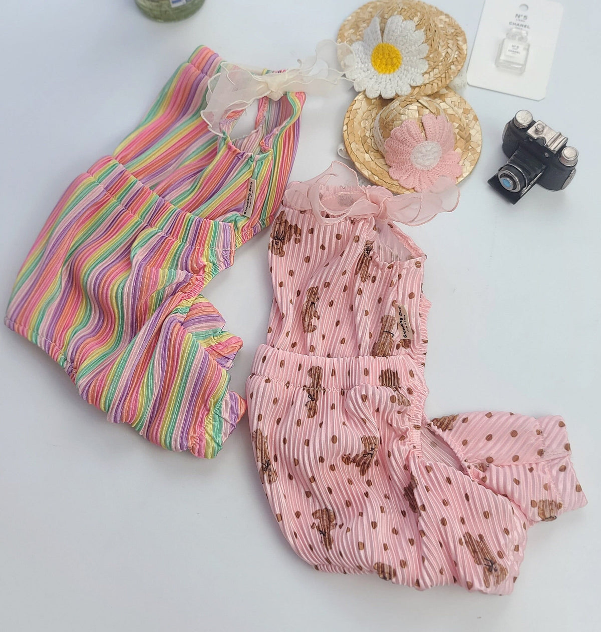 Two pet rompers: one multi-colored striped and one pink with a small brown pattern.