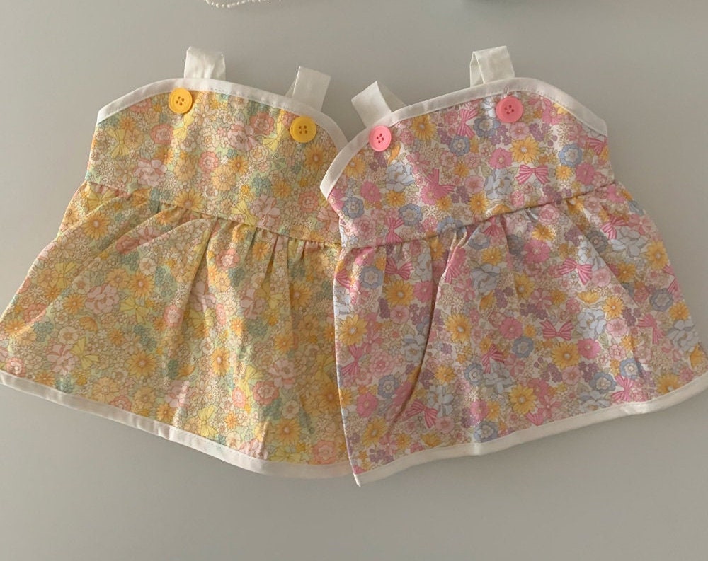Two NKpup vintage floral pet dresses with pink and yellow flower patterns and button details.