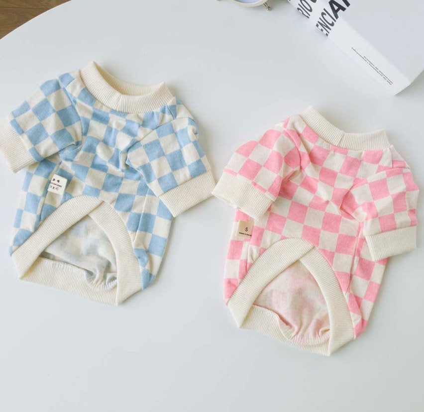 Two checkerboard pattern dog shirts in blue and pink colors.