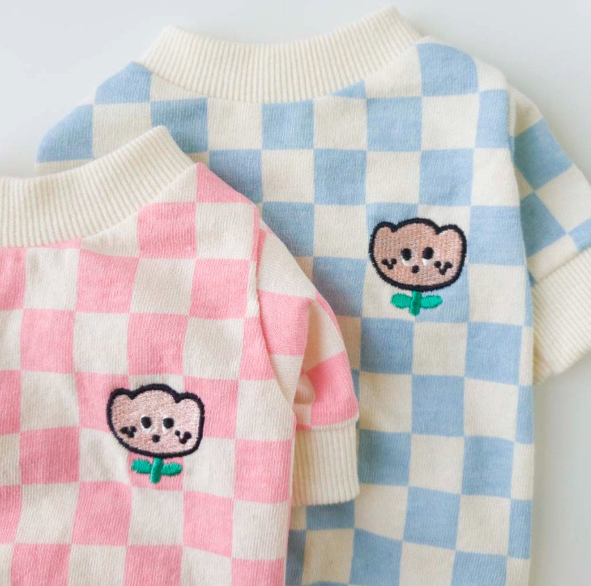 Two checkerboard dog shirts with tulip embroidery in pink and blue.