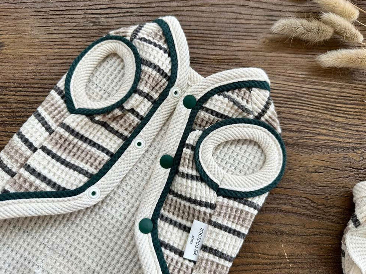Waffle stripe dog vest in cream and dark grey with green trim and snap buttons.