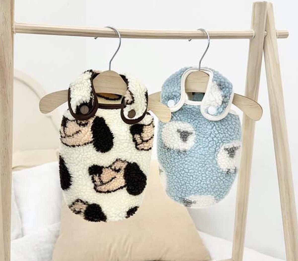 Two fleece dog sleep vests with animal face patterns, one in white with black spots and one in light blue.