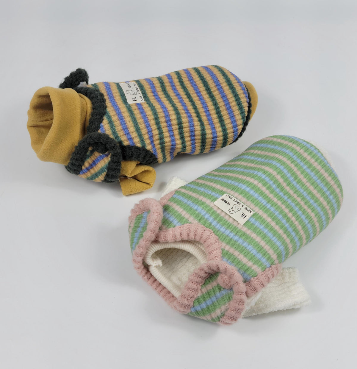 Two striped knit dog vests, one in yellow and blue and another in green and pink.