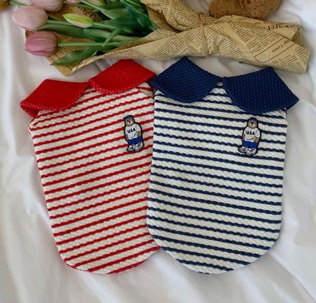 Two NKpup collared striped dog shirts, one red and white and one navy and white, featuring a teddy bear patch.