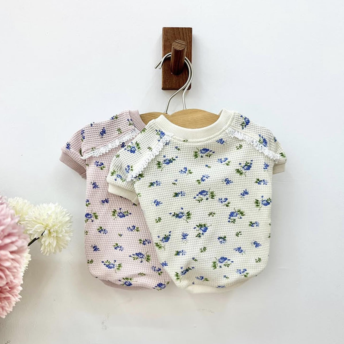 Two waffle floral dog shirts, one white with blue flowers and one pink with blue flowers, featuring lace trim.