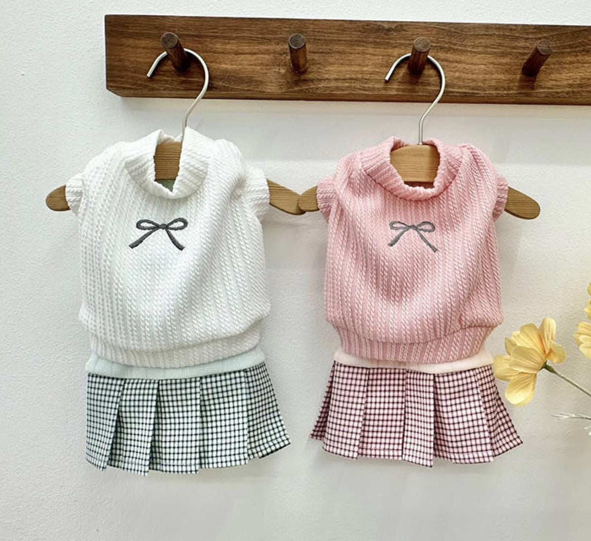 Two NKpup eyelet crop top pet outfits: one white with a black bow and plaid skirt, one pink with a grey bow and pink plaid skirt.