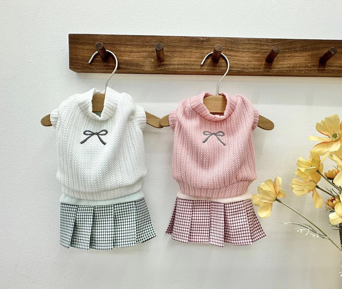 Two NKpup eyelet crop top pet outfits: one white with a black bow and plaid skirt, one pink with a grey bow and pink plaid skirt.