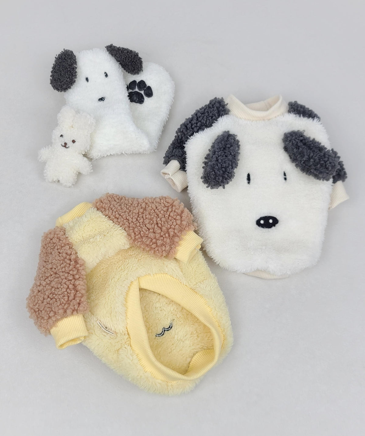 Fluffy ear dog sweatshirt in white with grey spots and a yellow and tan fleece dog vest.