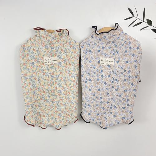 Two Blossom Ruffle Dog Shirts in floral patterns, one cream with orange flowers and one blue with blue flowers.